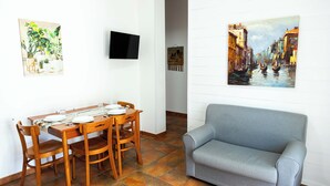 A dining area with a wooden table and chairs, a grey sofa, and two paintings on the walls. - APARTMENT IN SEA VIEW RESIDENCE, 200 METERS FROM THE BEACH WI FI (Alcamo)