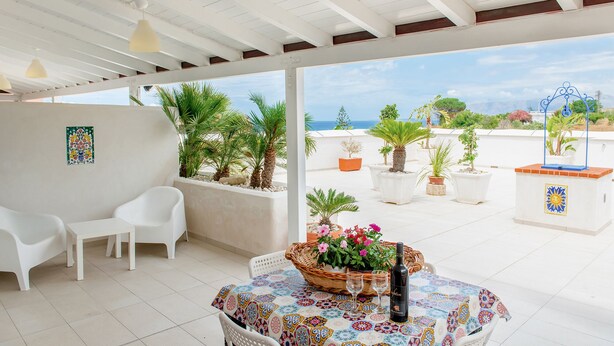 A covered patio with a table set for two, surrounded by potted plants and a view of the sea. - APARTMENT IN SEA VIEW RESIDENCE, 200 METERS FROM THE BEACH WI FI (Alcamo)