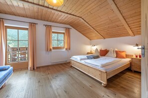 Une chambre avec un plafond en bois, un lit, une fenêtre et une chaise.
