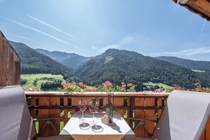 Une table avec des verres à vin et une bouteille, le tout placé sur fond de paysage montagneux.