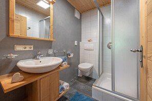 Une salle de bain avec un lavabo blanc, un miroir et une douche.