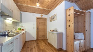 A kitchen with wooden cabinets, a sink, and a countertop with a basket of fruit.