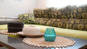 Una mesa con adornos, un sofá estampado y una pared con un cuadro enmarcado.