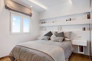 Een slaapkamer met een bed, nachtkastjes, een raam en ingebouwde planken.