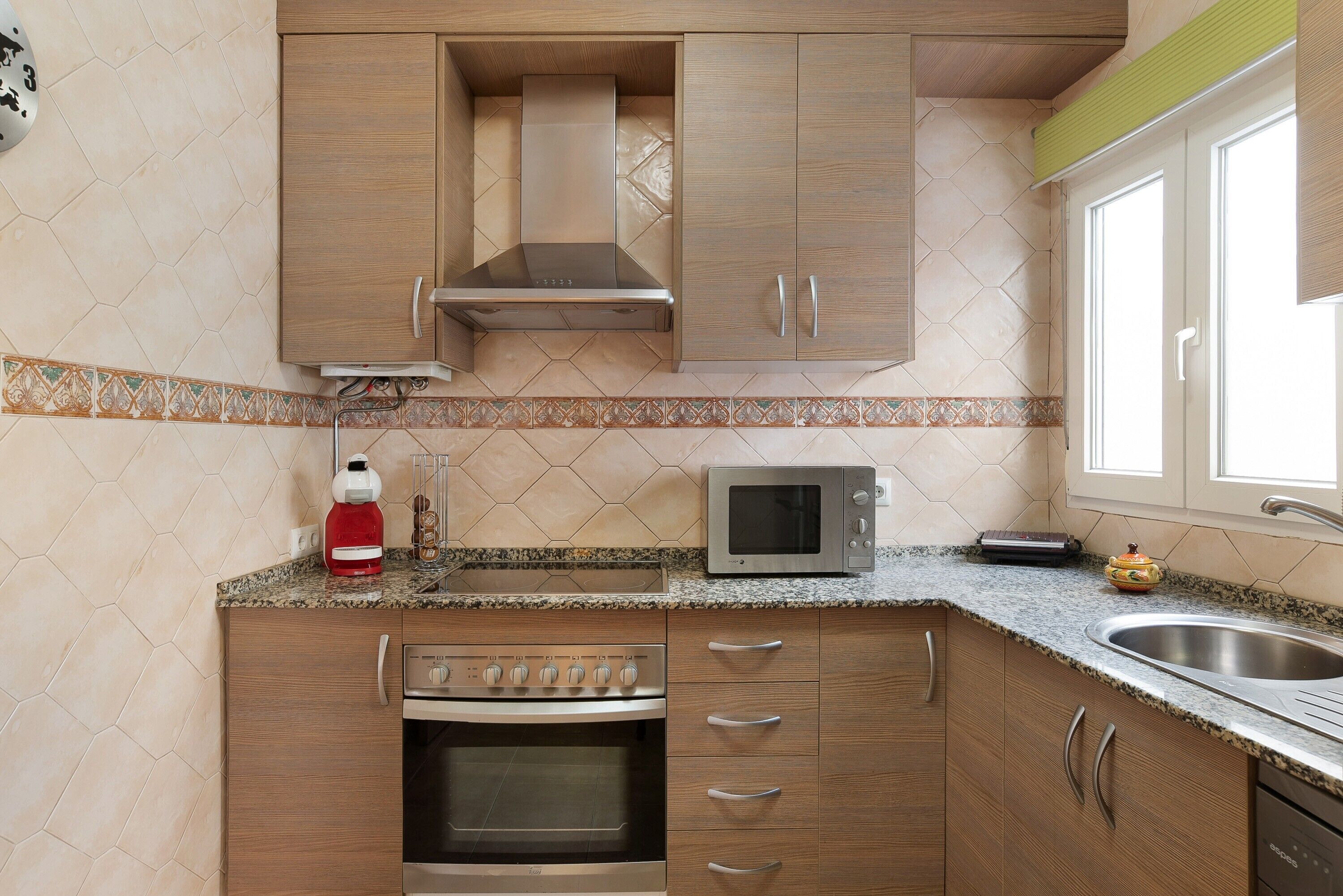 A kitchen with wooden cabinets, a stainless steel oven, a microwave, and a sink.