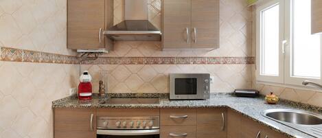 A kitchen with wooden cabinets, a stainless steel oven, a microwave, and a sink.