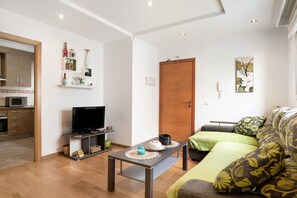 Un salon avec un téléviseur, un canapé et une table basse.