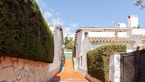 Un stretto sentiero in pietra che conduce a un edificio con tetto in tegole e una porta verde.
