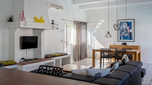 A living room with a TV, sofa, dining table, and chairs. - Villa 'Sea près des golfs-El Sol Naciente' with Mountain View, Pool and Wi-Fi (Santa Cristina d'Aro)