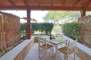 An outdoor patio with a table, chairs, and a bottle of wine.