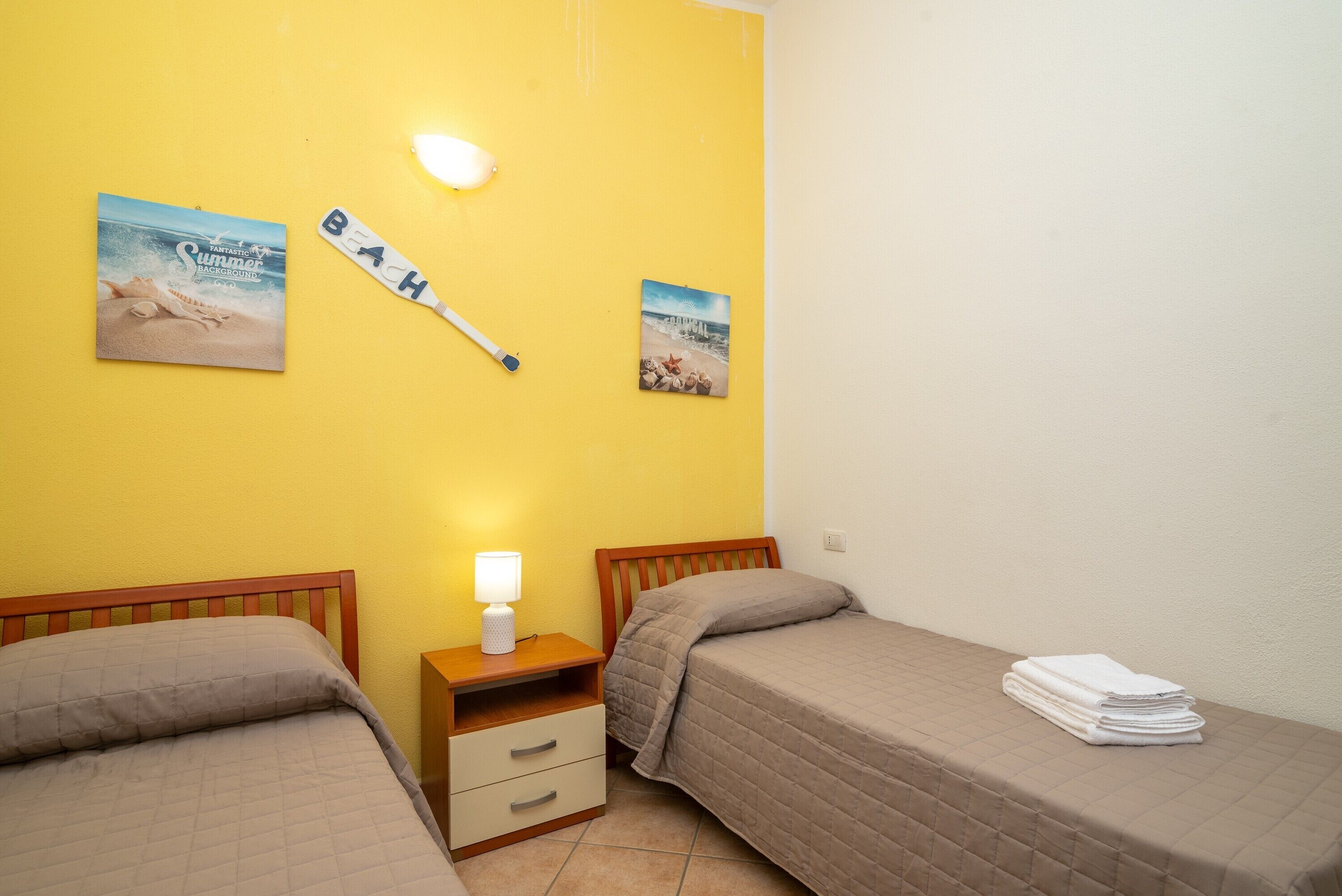 Ein Schlafzimmer mit zwei Betten, einem Nachttisch mit Lampe und zwei Bildern an der Wand.