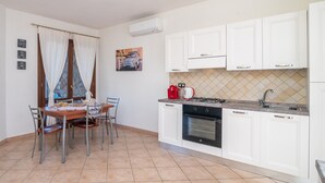 Una cocina compacta con alacenas blancas, estufa a gas y un lavamanos.