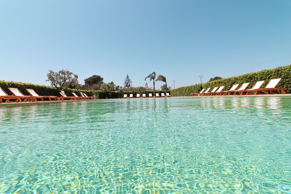 Une piscine aux eaux cristallines, bordée de chaises longues de chaque côté.