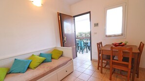 Une pièce comprenant un canapé, une table à manger avec des chaises, une fenêtre et une porte donnant sur l’extérieur.