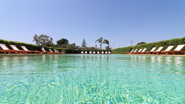Une piscine aux eaux cristallines, bordée de chaises longues de chaque côté.