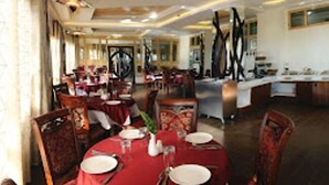 A dining area with round tables, red tablecloths, and wooden chairs. - Zone Connect Darjeeling (Darjeeling)