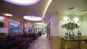 A hotel lobby with a long reception desk, seating area with sofas, and a wall with decorative items. - Zone Connect Darjeeling (Darjeeling)