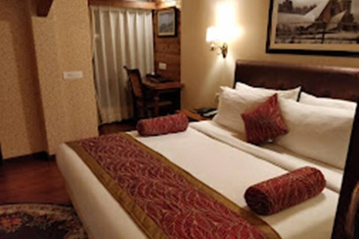 A hotel room with a large bed, a desk, and a chair.