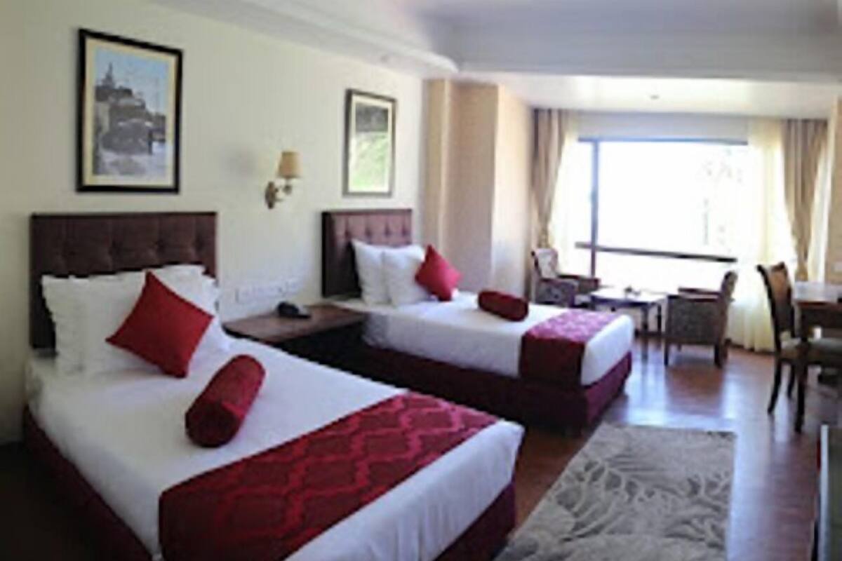 A hotel room with two beds, a desk, and a chair.
