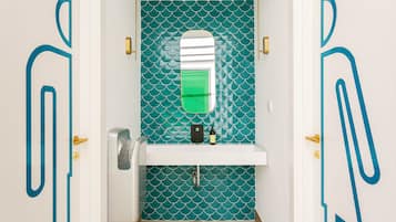 A bathroom with teal patterned tiles, a white sink, and a mirror.