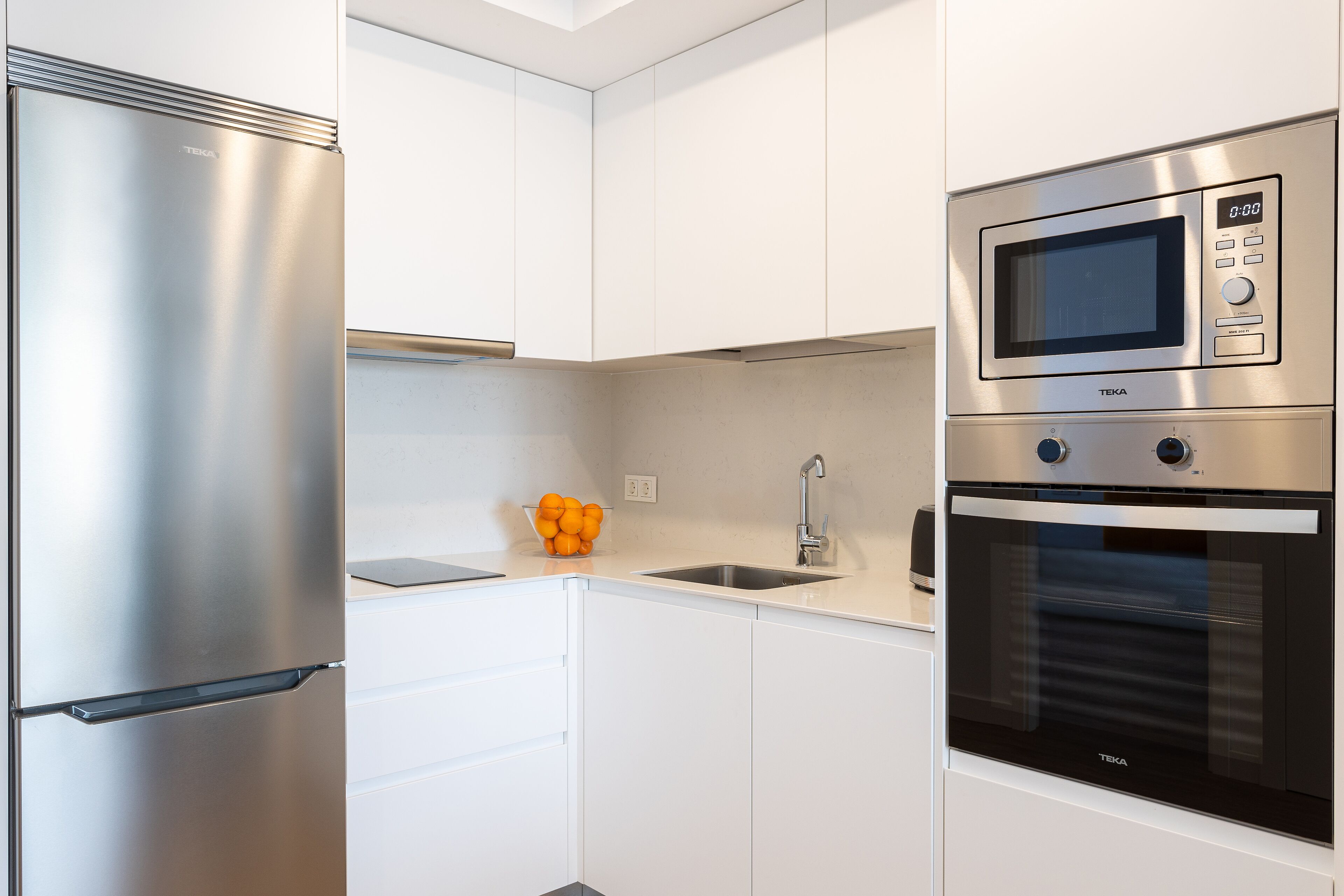 Una cocina moderna con un refrigerador de acero inoxidable, un microondas integrado y un horno.