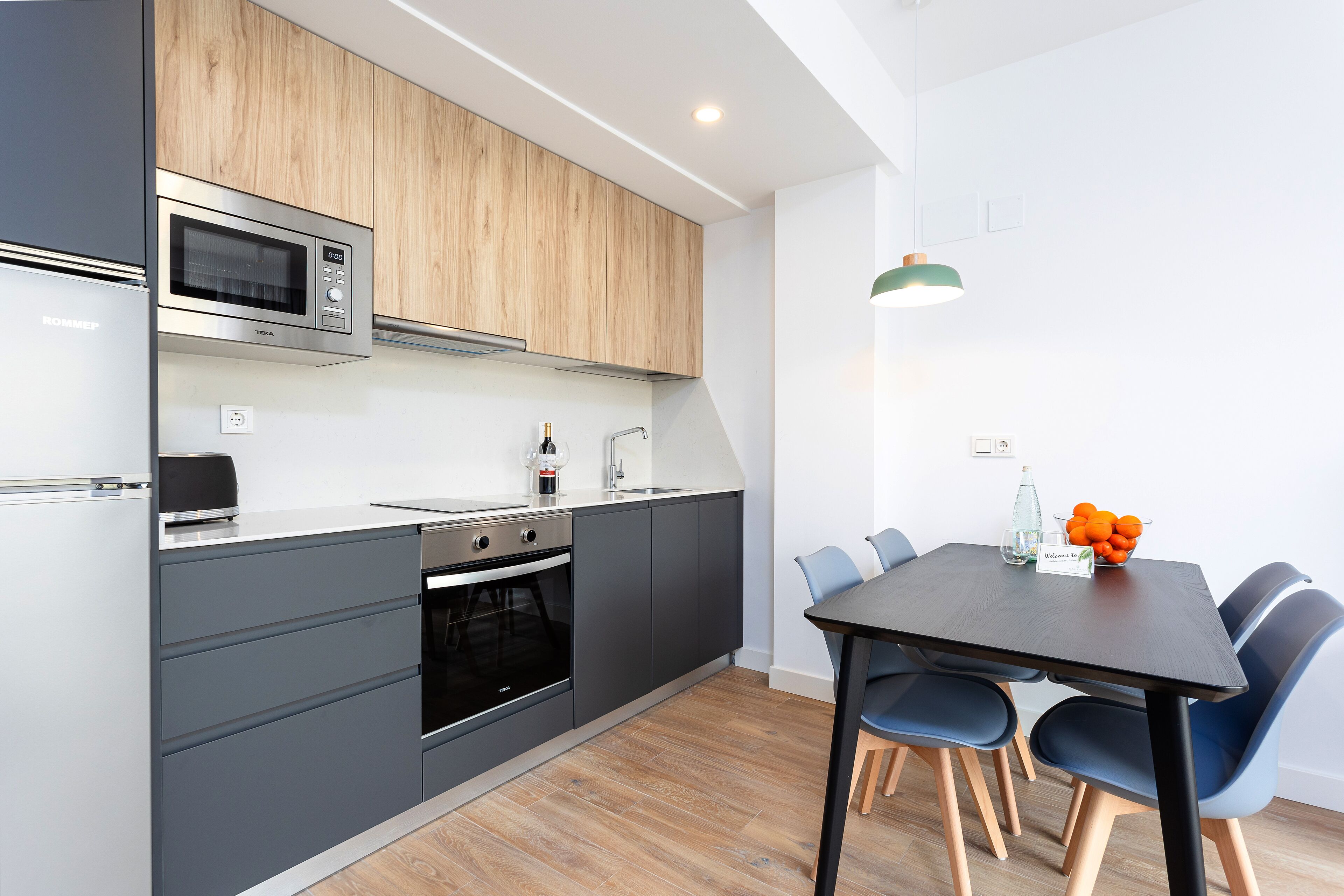 Une cuisine moderne équipée d’un four à micro-ondes, d’un four et d’un évier intégrés, ainsi qu’un coin repas avec une table et des chaises.