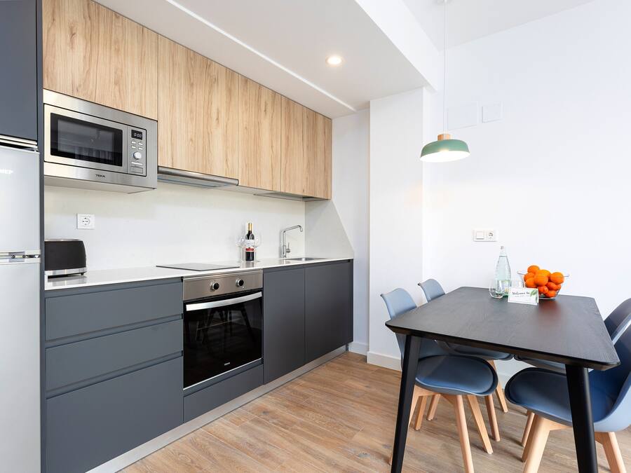 Une cuisine moderne équipée d’un four à micro-ondes, d’un four et d’un évier intégrés, ainsi qu’un coin repas avec une table et des chaises.