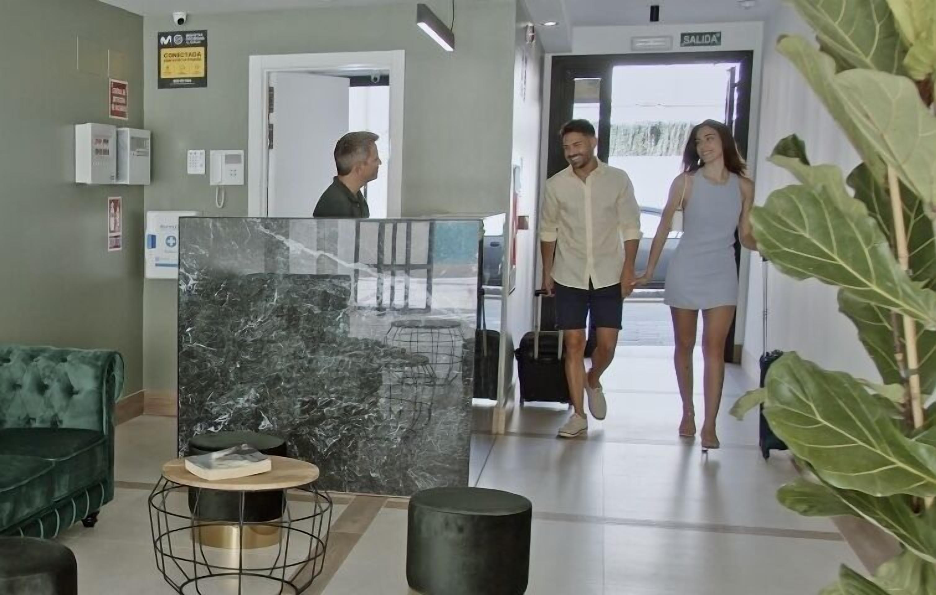 A reception area with a marble reception desk, a green sofa, and a plant.