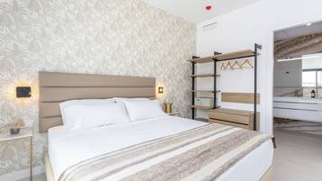 A modern bedroom with a large bed, a nightstand, a wall-mounted shelf, and a mirror.