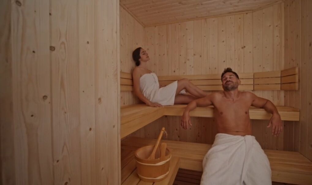 Un sauna avec des bancs en bois et un seau en bois accompagné d’une louche.