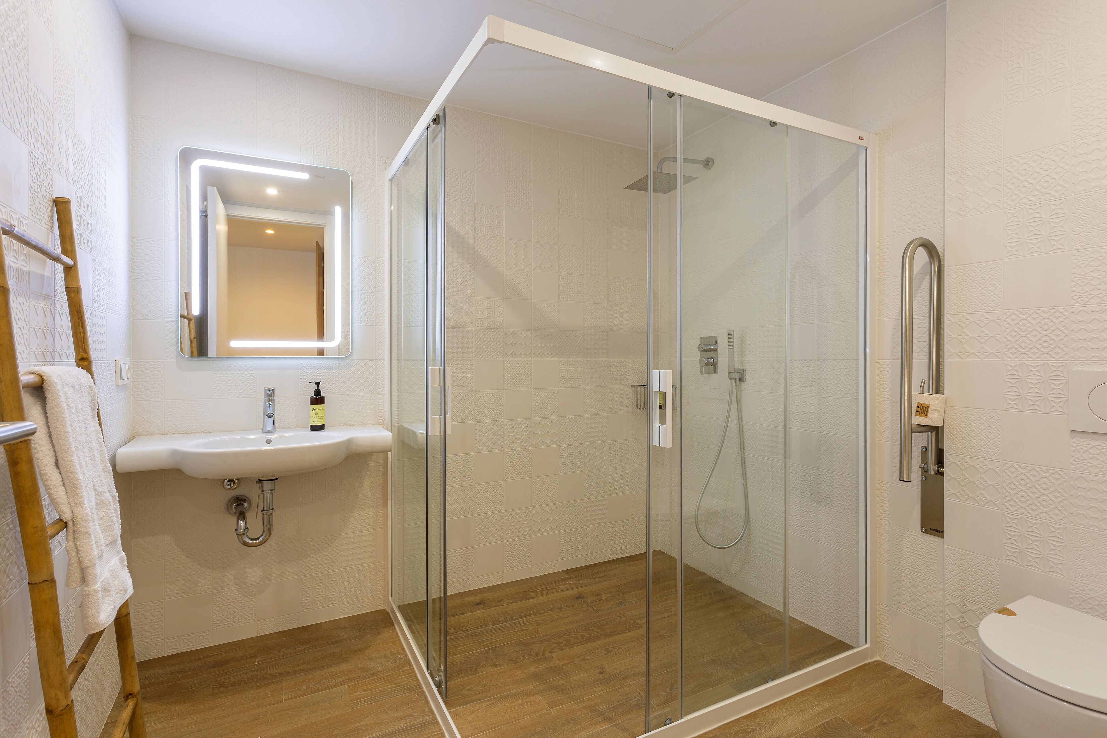 A modern bathroom with a glass-enclosed shower, a sink with a mirror, and a toilet.