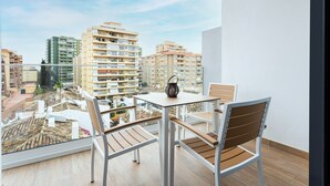 A balcony with a table and chairs, offering a view of surrounding buildings. - Caleyro Boutique Apartments - Parking incluido (Fuengirola)