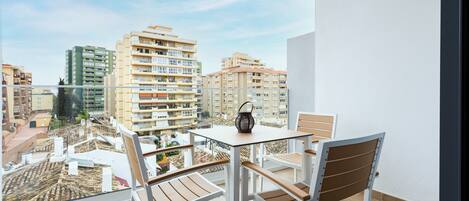 A balcony with a table and chairs, offering a view of surrounding buildings.