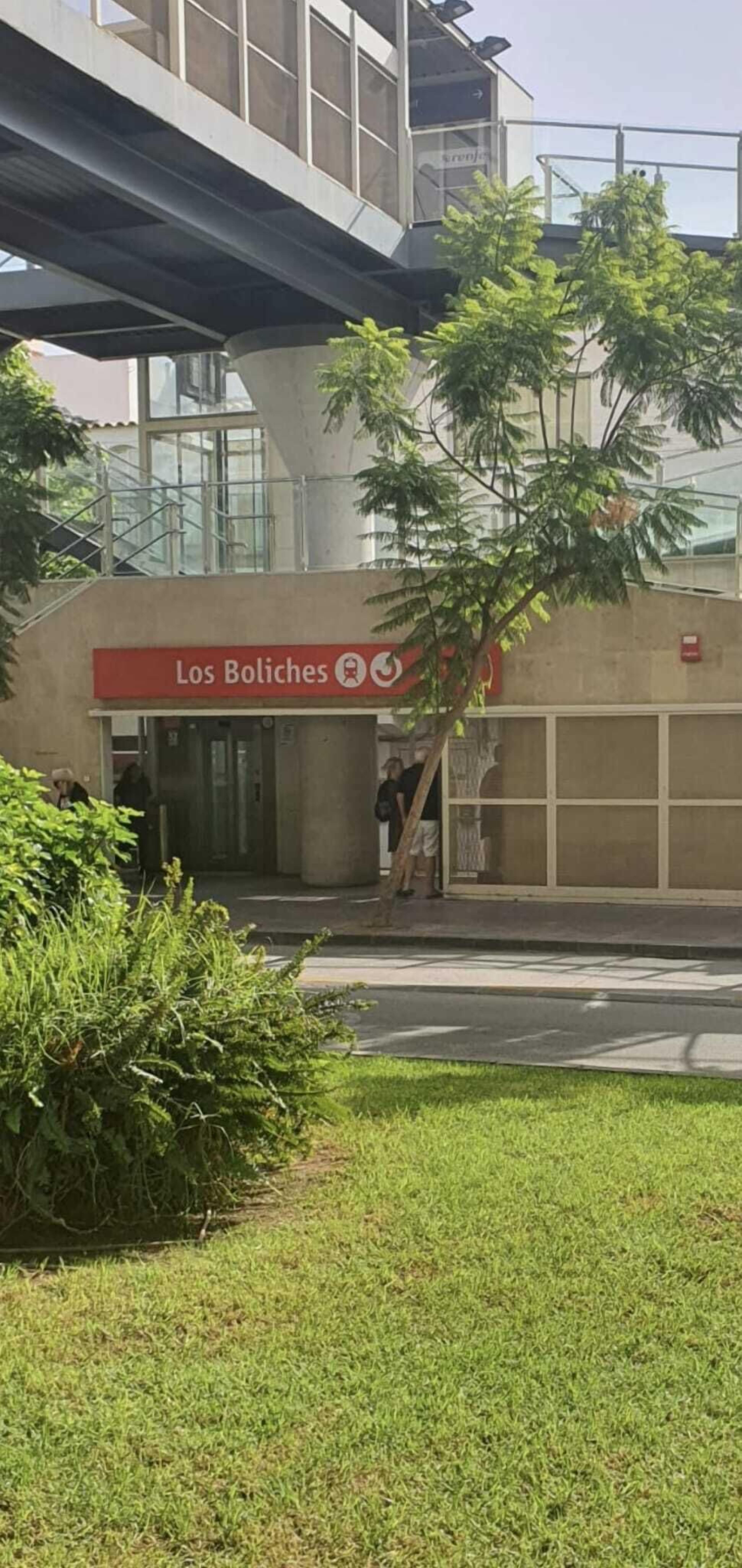 A building with a sign reading "Los Boliches" and a staircase leading to an upper level.