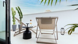 A balcony with a chair, potted plants, a small table, and a decorative lantern. - Caleyro Boutique Apartments - Parking incluido (Fuengirola)