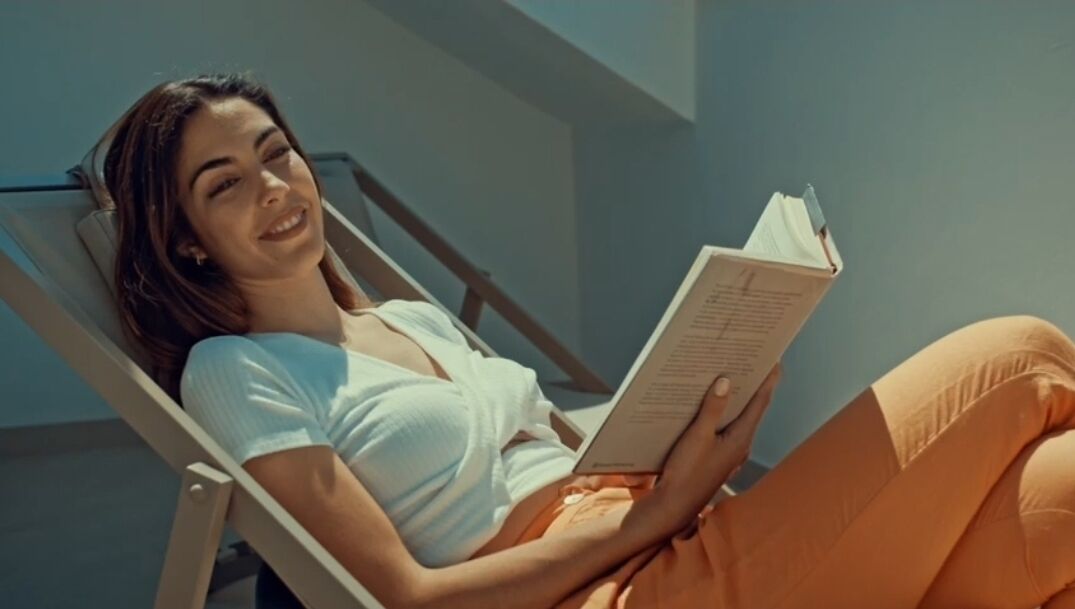 Eine Person liegt auf einer Liege und liest ein Buch.