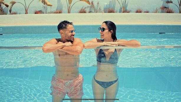 Two people standing at the edge of a swimming pool with clear water, surrounded by a poolside area with plants and a clear sky. - Caleyro Boutique Apartments - Parking incluido (Fuengirola)
