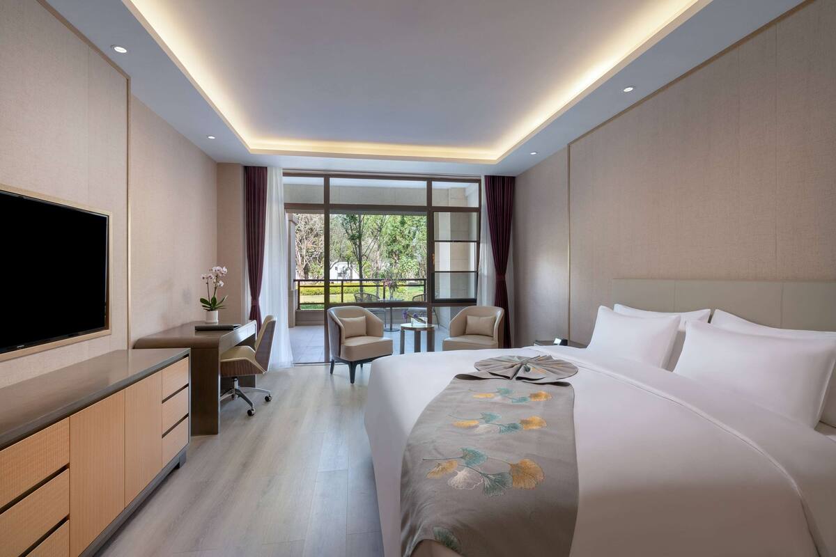 Een hotelkamer met een groot bed, een televisie, een bureau en uitzicht op het omliggende landschap.