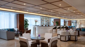 A spacious lobby with a seating area, a reception desk, and a large window providing natural light.