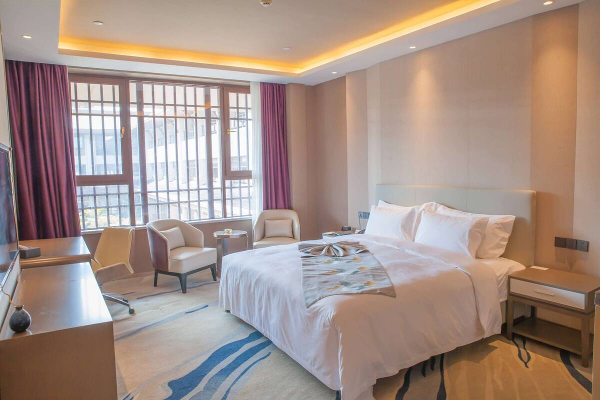 Een hotelkamer met een groot bed, een bureau, een stoel en een klein tafeltje.