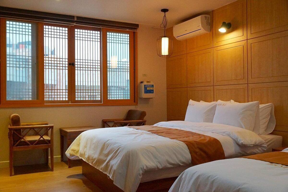 A hotel room with a large window, a bed, a chair, and a bedside table.
