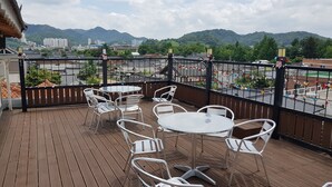 A balcony with metal chairs and tables, overlooking a cityscape and mountains. - Hwangsil Tourist Hotel (Jeonju)