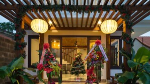 A covered entrance with a wooden pergola, two large lanterns, and a Christmas tree. - Hoi An Maison Vui Villa (Da Nang Municipality)
