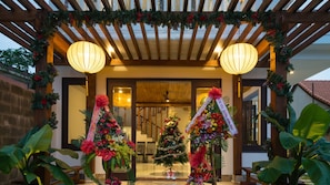 Welcome to our festive hotel entrance, featuring a beautifully decorated Christmas tree, floral arrangements, and a charming pergola.