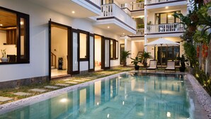 A modern hotel with a swimming pool, outdoor seating, and multiple balconies. - Hoi An Maison Vui Villa (Da Nang Municipality)