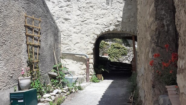 Une ruelle étroite, bordée de murs en pierre et dotée d’une porte en bois.