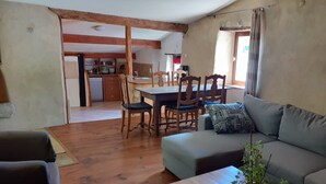 Un salon comprenant un canapé, une table basse avec une plante, un plancher en bois et un coin repas avec des chaises et une table.