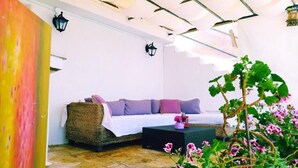 Una habitación acogedora con un sofá de mimbre, una mesita pequeña y una planta en maceta.