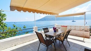 Una terraza con mesa y sillas, con vista a una masa de agua y barcos.