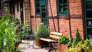 A brick building with green windows and a wooden bench in the foreground.